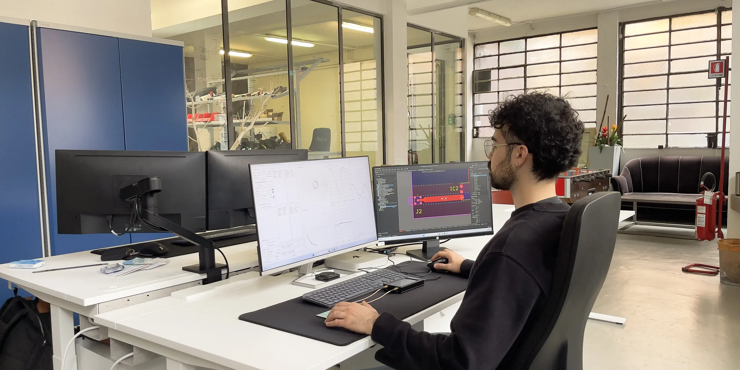 Engineer at the workstation with schematic and layout on screen
